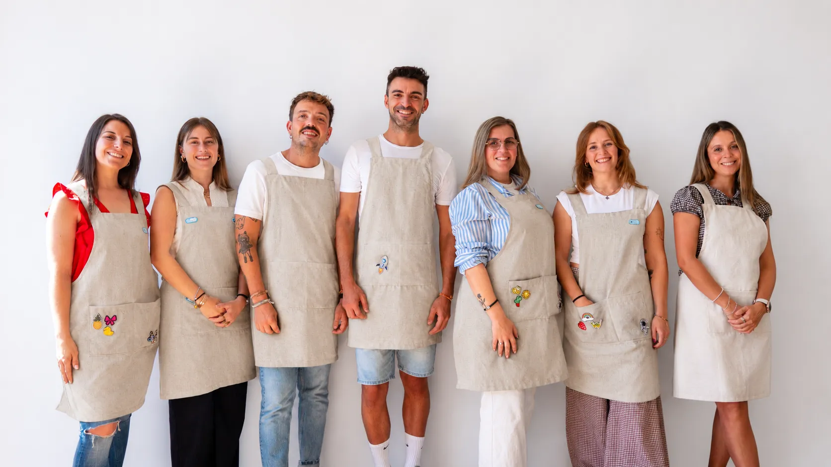El equipo de Astronauta sonriendo con sus delantales frente a una pared blanca
