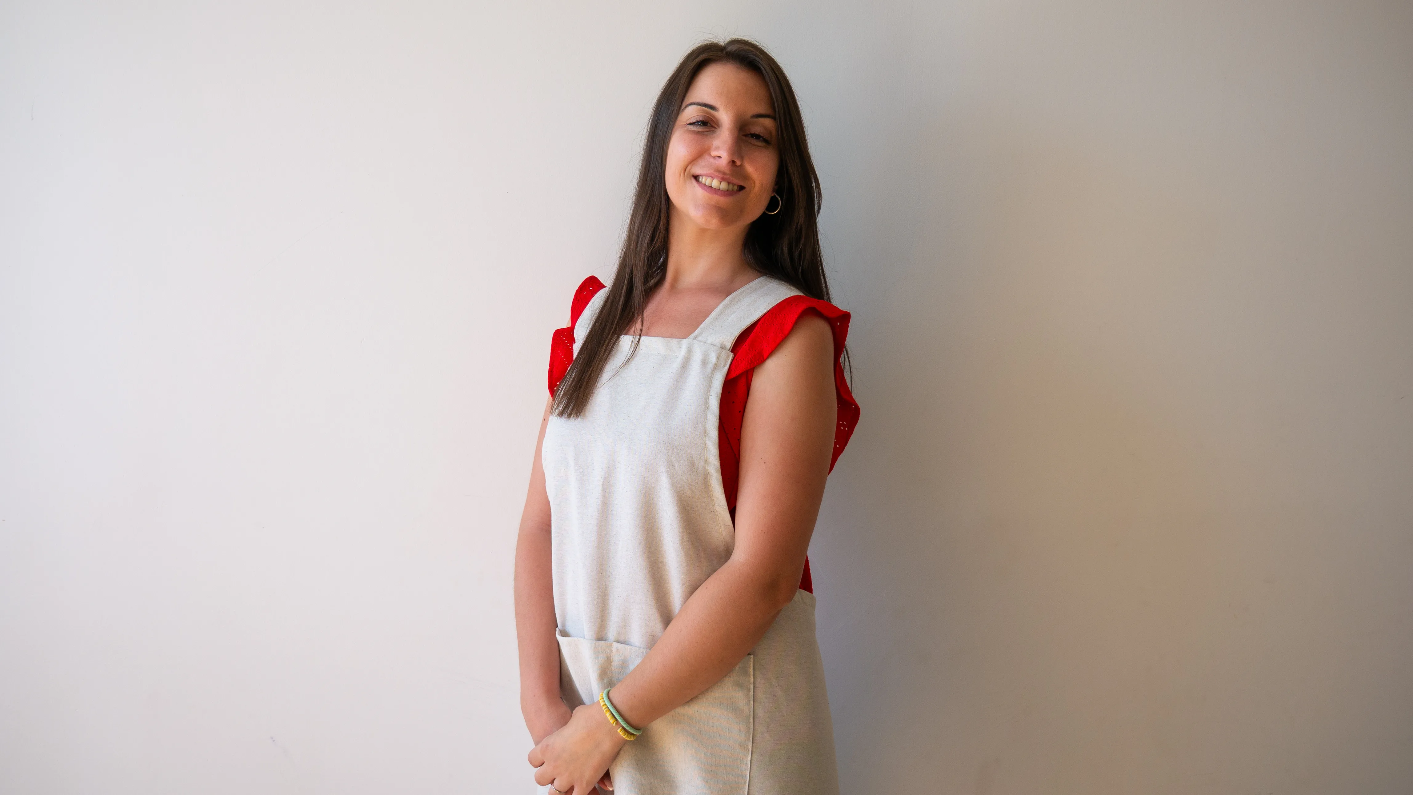 Bárbara Turco, maestra especialista en audición y lenguaje, sonriendo con su delantal frente a una pared blanca