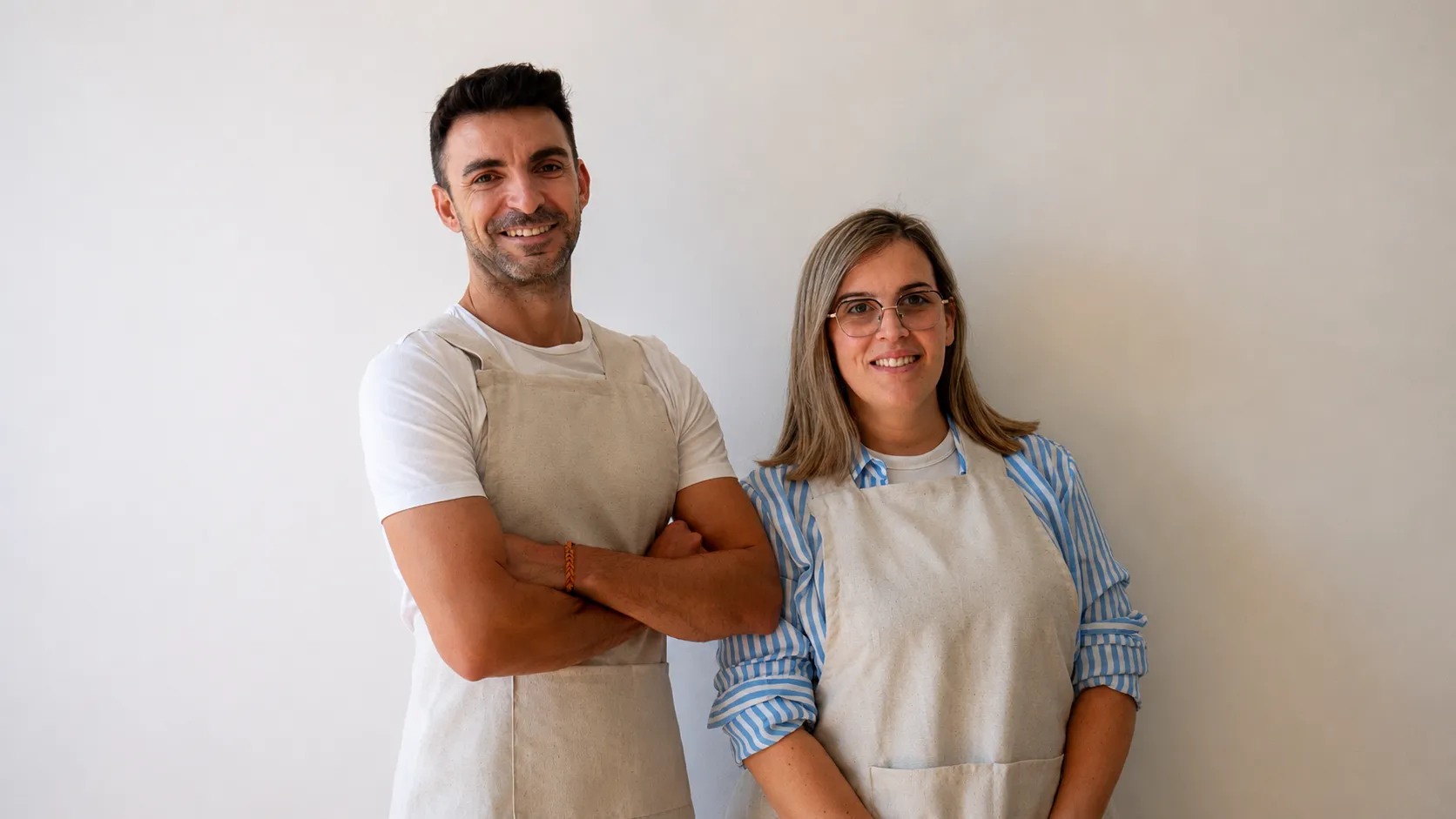 Brais Cao y Noemi Durán, del equipo de pedagogía, sonriendo con sus delantales frente a una pared blanca