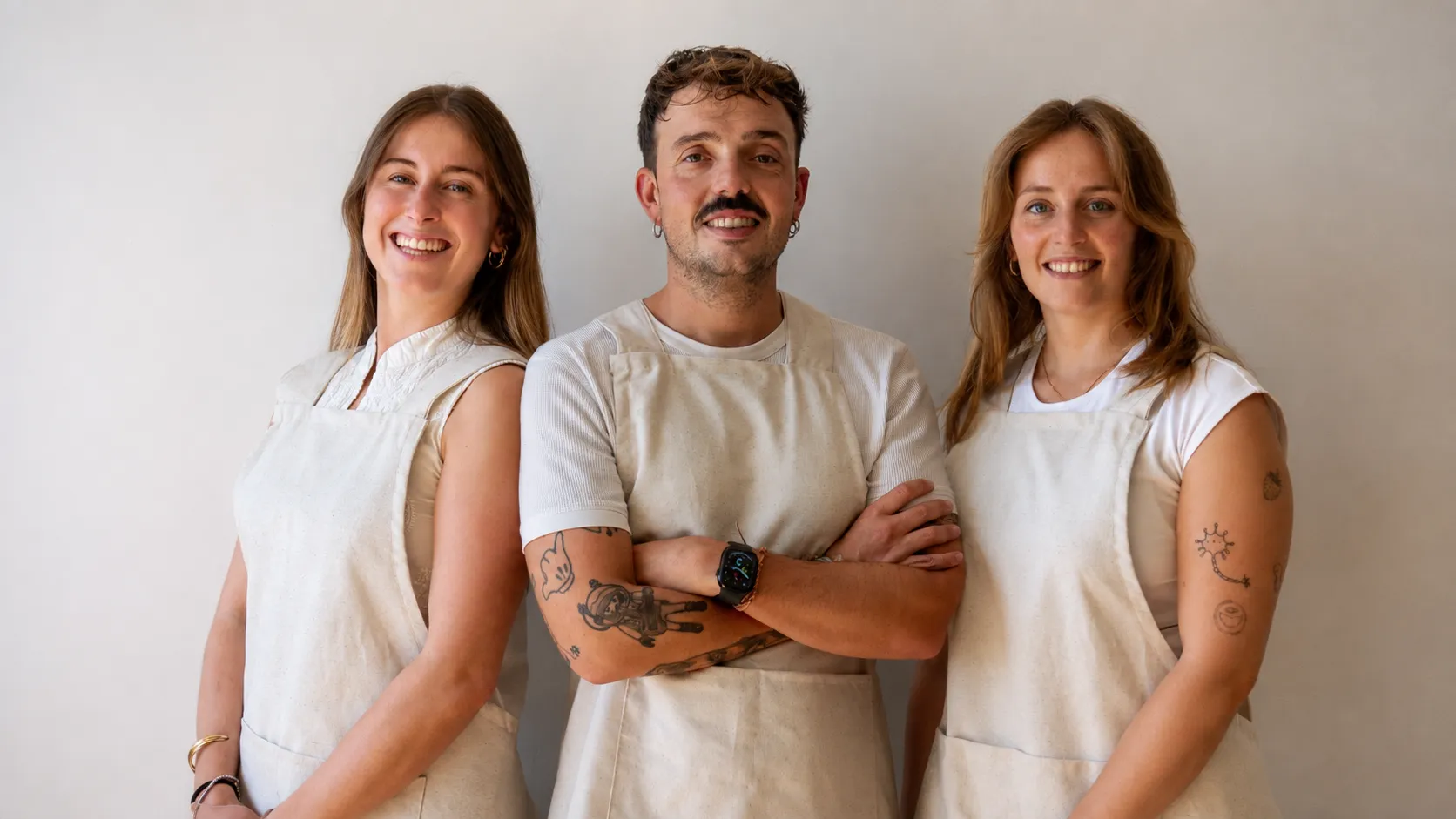 Irene Rodríguez, Miguel Casal y Alicia Buide, del equipo de psicología, sonriendo con sus delantales frente a una pared blanca